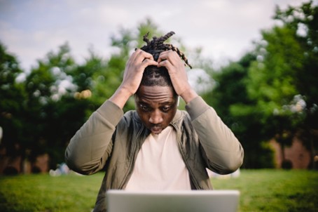 Man looking shocked at his laptop in a park